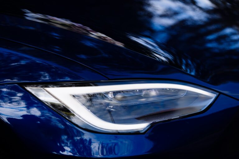 Closeup of new projector headlight on the modern blue car.